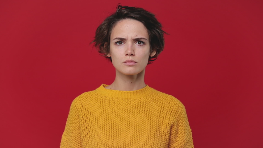 Angry mad young woman 20s years old in yellow sweater posing isolated on red background in studio. People sincere emotions lifestyle concept. Looking at camera screaming scolding protest waving hands Royalty-Free Stock Footage #1060853506