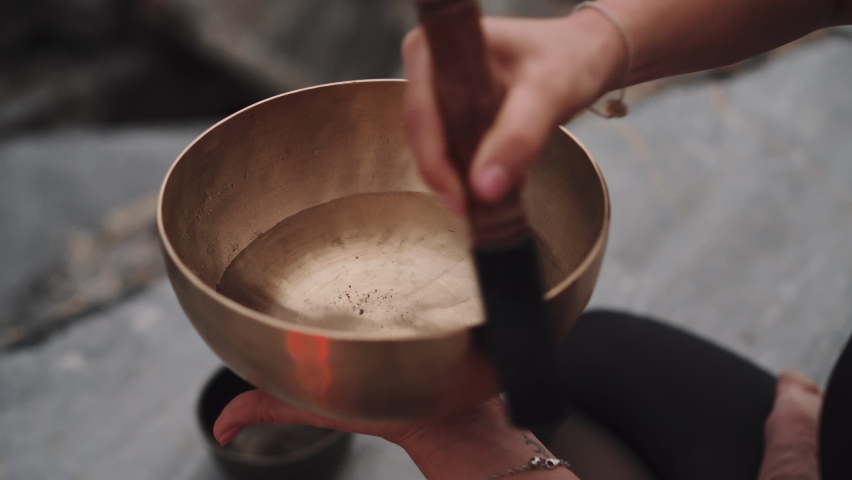 Yoga girl playing on a tibetan bowl with water and splashes
