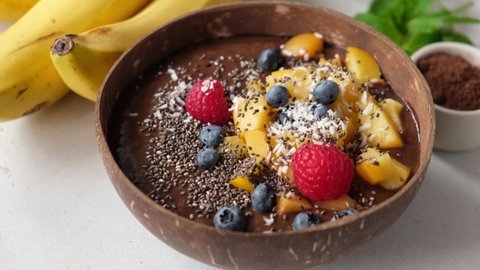 Vegan chocolate smoothie bowl with superfoods rotating. Healthy superfood smoothie with fruits and seeds
