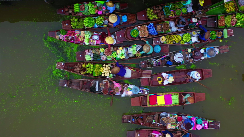 Aerial view famous floating market in Thailand, Damnoen Saduak floating market, Farmer go to sell organic products, fruits, vegetables and Thai cuisine, Tourists visiting by boat, Ratchaburi, Thailand | Shutterstock HD Video #1060858444