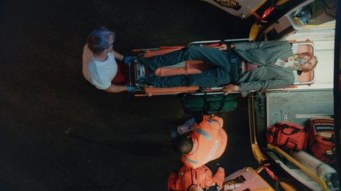 Footage from Above of a Team of EMS Paramedics Bringing Injured Patient to Hospital and Get Him Out of Ambulance on a Stretcher. Emergency Care Assistants Help Young Man to Stay Alive After Accident.