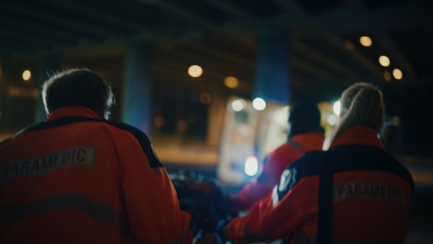 Team of EMS Paramedics React Quick to Provide Medical Help to Injured Patient and Get Him in Ambulance on a Stretcher. Emergency Care Assistants Arrived on the Scene of a Traffic Accident on a Street. Royalty-Free Stock Footage #1060859677