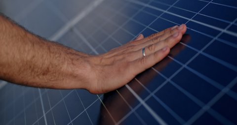 Close up view of male engineer hand touching photovoltaic electric solar panel battery. Concept of solar park, green renewable energy and innovations