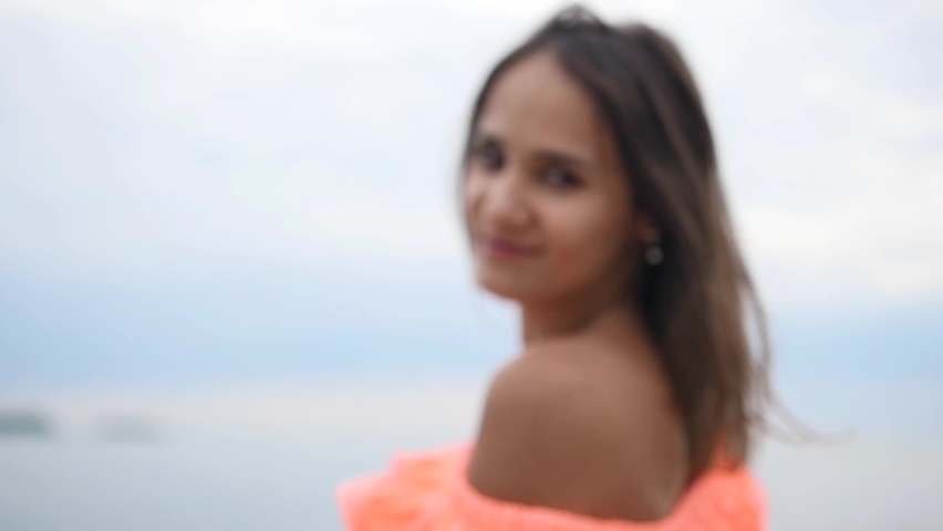 Slow motion. Portrait of a young beautiful woman in a bright dress by the sea on a cloudy day