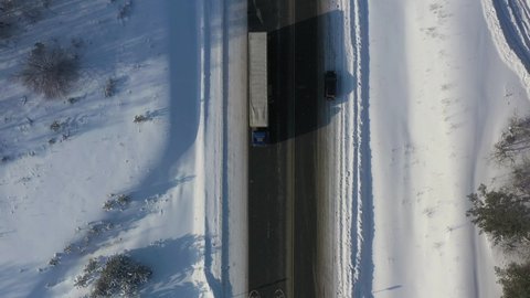 AERIAL. Top view to the truck driving on the snow road in winter time. Delivery concept