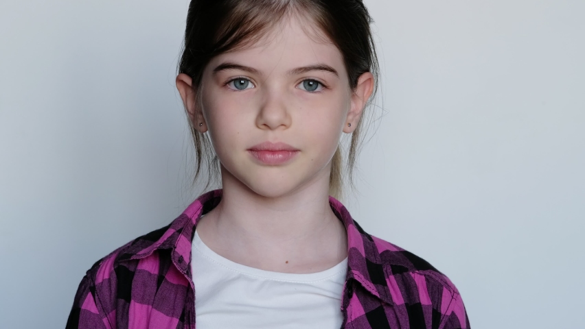 little / young cheerful smiling girl in a pink plaid shirt showing thumb up, ok sign.  On white background.