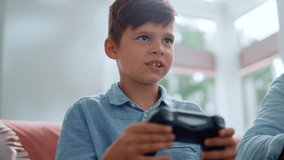 Portrait of serious boy using gamepad for computer game. Male gamer pushing buttons on joystick. Happy boy winning video game at home. Closeup excited child celebrating victory after game competition