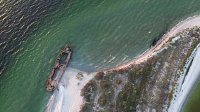 Aerial video flying over old shipwreck reinforced concrete barge abandoned stand on beach on the coast of Black sea in Kinburn peninsula, Ukraine. 4k UHD drone footage