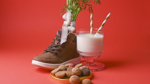 Dutch holiday Sinterklaas. hildrens shoe with carrots for Santa's horse, pepernoten and sweets on a bright background. A gloved hand takes the liver and puts on a protective mask. Stop mo