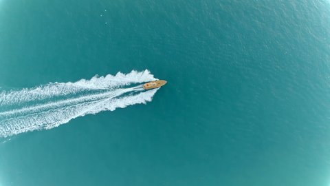 White Luxury Yacht sailing on clean blue sea surface. Aerial Drone Shot Over Speed Boat with small waves in Ocean. Fast speedboat in the clear turquoise magical sea from above.