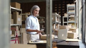 Older female online store ecommerce small business owner, warehouse worker, merchant seller packing shipping package using mobile app preparing delivery parcel box. Dropshipping distribution. - Powered by Shutterstock - Get 15% off with code: PIKWIZARD15