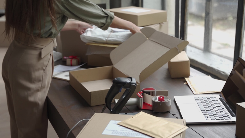 Close up view of female online store small business owner worker packing package post shipping ecommerce retail order gift in box preparing delivery parcel on table. Dropshipping shipment service. Royalty-Free Stock Footage #1060886401