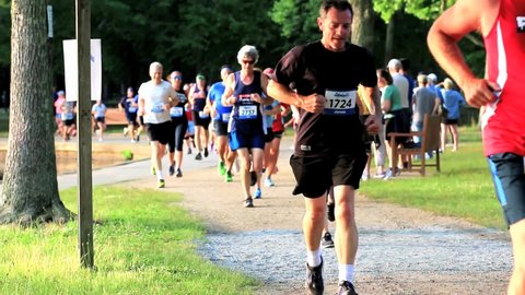 North Babylon, New York, USA – 9 July 2019: Many runners racing around Belmont Lake during a summer 5K trail race.
