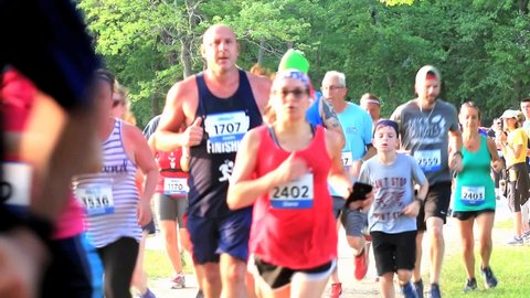 North Babylon, New York, USA – 9 July 2019: Many runners racing around Belmont Lake during a summer 5K trail race.