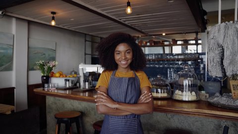 Clip of exquisite mixed raced cafe owner smiling crossed armed standing in trendy coffee shop.