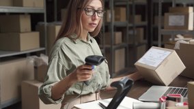 Young female seller or online store worker scanning parcel packing ecommerce post shipping box checking online retail store orders fulfillment using laptop in dropshipping delivery service warehouse. - Powered by Shutterstock - Get 15% off with code: PIKWIZARD15