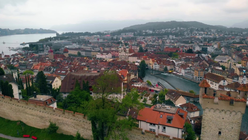 Aerial view over the Nolliturm tower, towards the city of Lucerne and the Reuss river, on a overcast, summer day, in Switzerland - orbit, drone shot Royalty-Free Stock Footage #1060893043