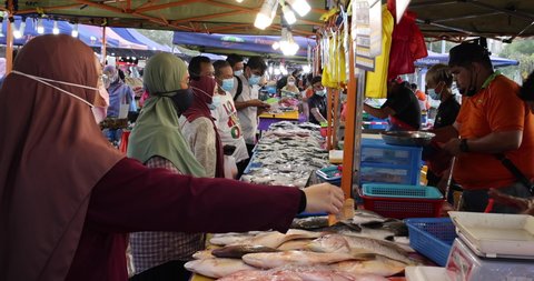 Putrajaya, Malaysia - October 16, 2020: Street food night market at  Putrajaya, near Kuala Lumpur. Malaysian women with face mask and hijab buy seafood in a fresh market. Female Malay choose seafood 