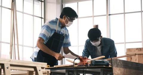 Middle age carpenter man with Asian young man working at workshop room at home to making premium masterpiece carpentry. 