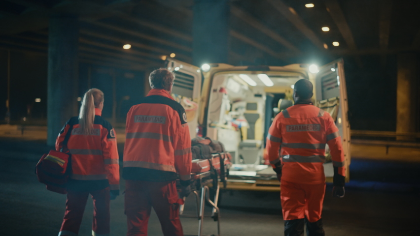 Team of EMS Paramedics React Quick to Provide Medical Help to Injured Patient and Get Him in Ambulance on a Stretcher. Emergency Care Assistants Arrived on the Scene of a Traffic Accident on a Street. Royalty-Free Stock Footage #1060901110