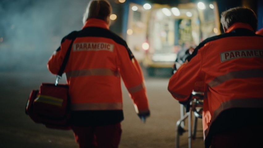Team of EMS Paramedics React Quick to Provide Medical Help to Injured Patient and Get Him in Ambulance on a Stretcher. Emergency Care Assistants Arrived on the Scene of a Traffic Accident on a Street. Royalty-Free Stock Footage #1060901113