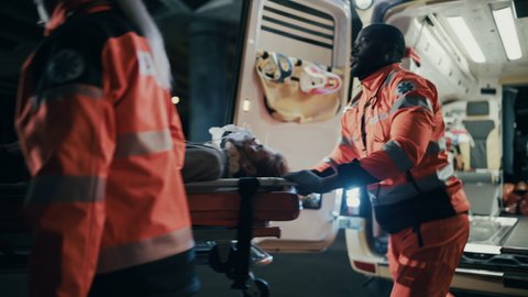 Team of EMS Paramedics React Quick to Bring Injured Patient to Healthcare Hospital and Get Him Out of Ambulance on a Stretcher. Emergency Care Assistants Help Young Man to Stay Alive After Accident.