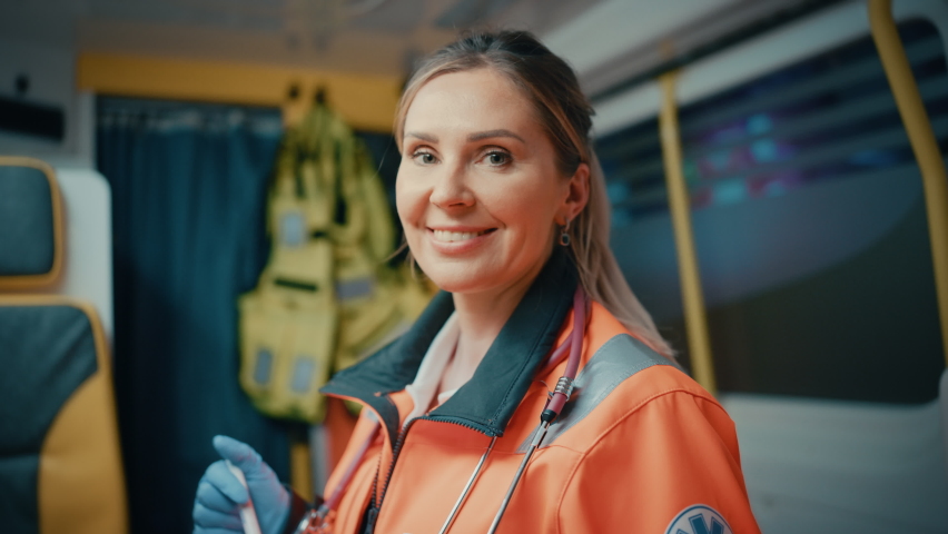 Calm and Happy Female EMS Professional Paramedic Smiles on Camera in Ambulance Vehicle. Successful Emergency Medical Technician on Their Way to a Call Outside the Healthcare Hospital. | Shutterstock HD Video #1060901233