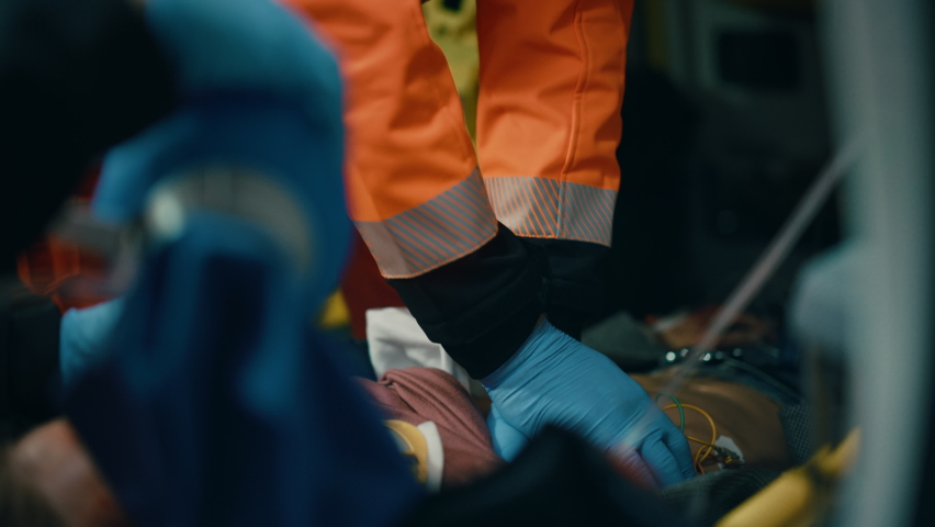 EMS Paramedics Team Provide Medical Help to Injured Patient on the Way to Hospital. Emergency Care Assistants Perfroming Cardiac Massage to Bring the Man Back to Life in an Ambulance.