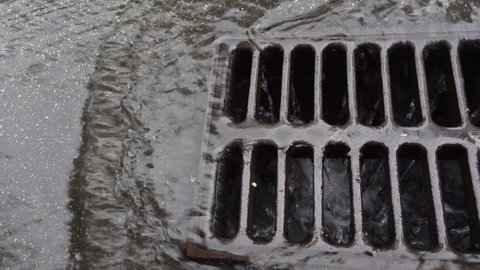 4K view of rainwater pouring into road storm runoff