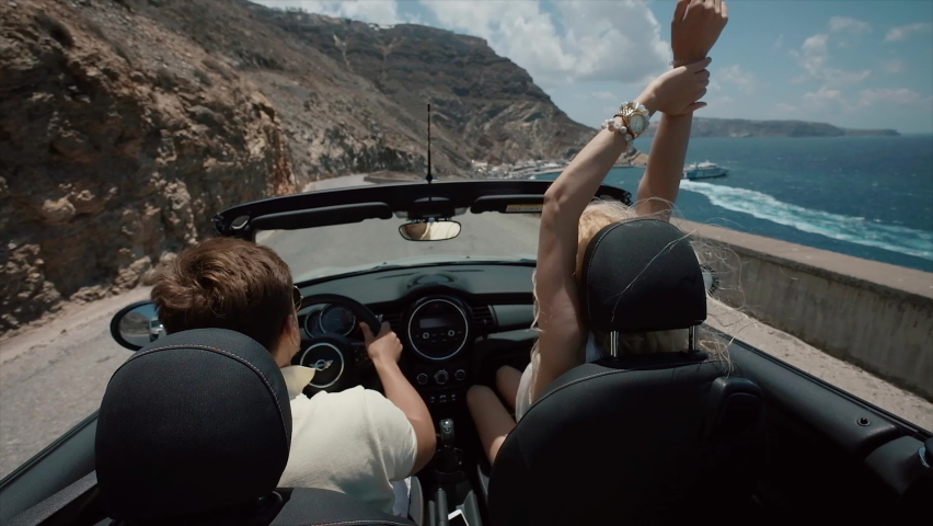 Young Couple Riding A Car On A Mountainside. Santorini Island Greece. Young Blonde And Pretty Guy Enjoy Vacation. Unsurpassed Landscape. | Shutterstock HD Video #1060906480