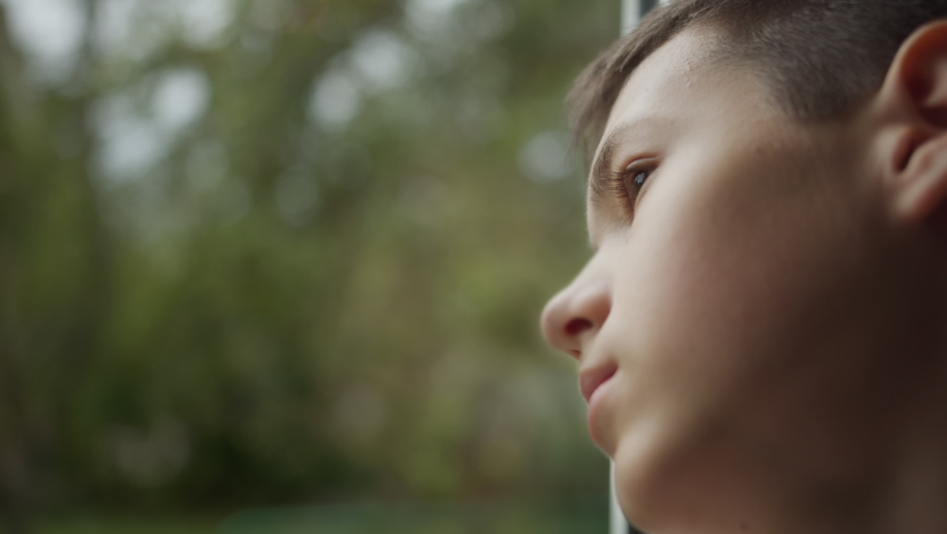 Portrait of a sad boy looking out the window, thinking about something | Shutterstock HD Video #1060908700