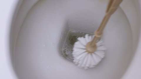 Cleaning and Washing Toilet Bowl with Brush. House Cleaning Service Concept. Housewife washes white toilet with a brush. Does general cleaning. House cleaning service concept. Close-Up. Slow Motion