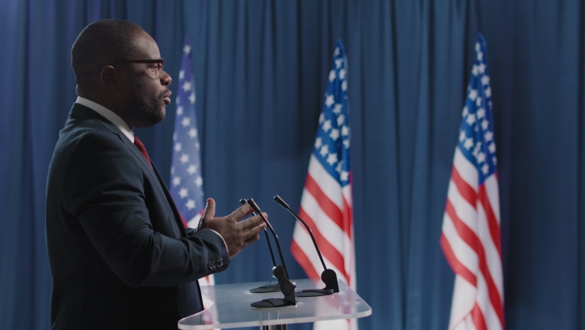 Side view shot footage of African American man running for presidency speaking about reforms while debating