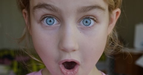 Child Girl Looks and Is Surprised Happy to Receive Surprise. Portrait Little Kid With Blue Eyes Looking at Camera Closeup. Surprised Girl Face. Close up of Shocked Child Face Expression. Wow Emotion.