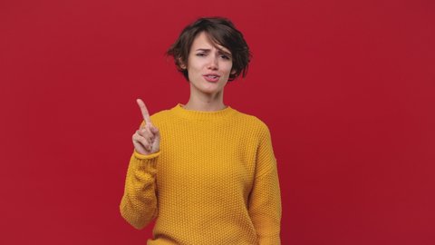 Fun young woman 20s years old in yellow sweater isolated on red wall background in studio. People lifestyle concept. Looking camera pointing fingers herself ask say who me no thanks i do not need it
