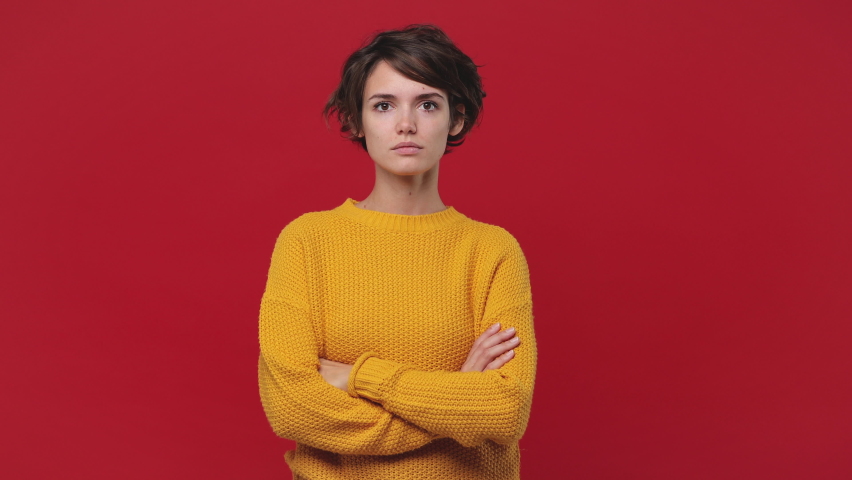 Smiling beautiful young woman girl 20s years old in yellow sweater posing isolated on red background in studio. People sincere emotions lifestyle concept Looking camera charming smile wink blink eye | Shutterstock HD Video #1060922230