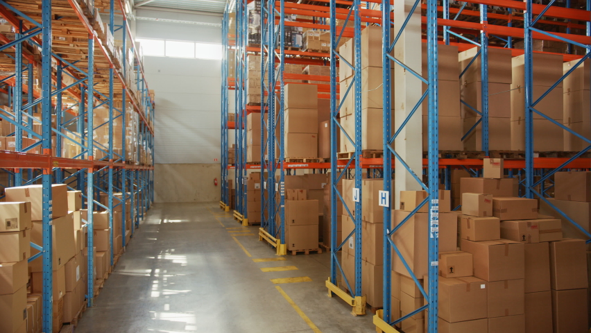 Gigantic Sunny Retail Warehouse full of Shelves with Goods in Cardboard Boxes. Logistics and Distribution Storehouse Center for further Product Delivery Packages. Descending Semi Side Camera View | Shutterstock HD Video #1060923280