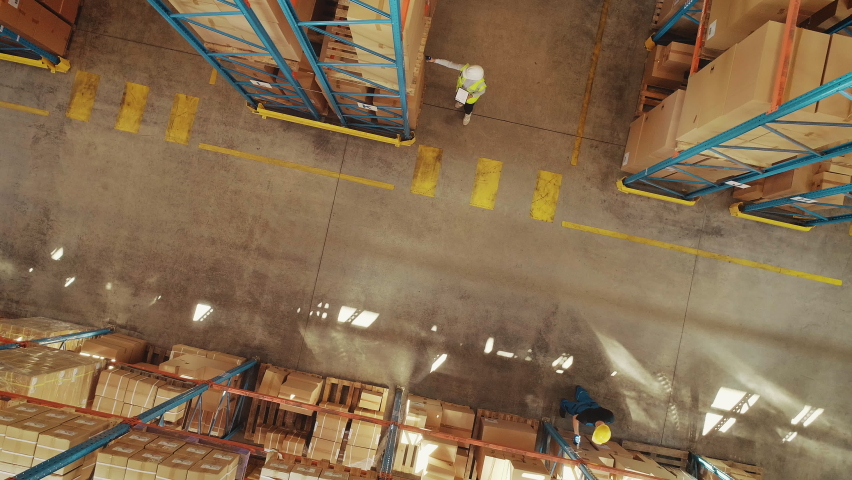 Top-Down View: In Warehouse People Working, Forklift Truck Operator Lifts Pallet with Cardboard Box. Logistics, Distribution Center with Products Ready for Global Shipment, Customer Delivery Royalty-Free Stock Footage #1060923313
