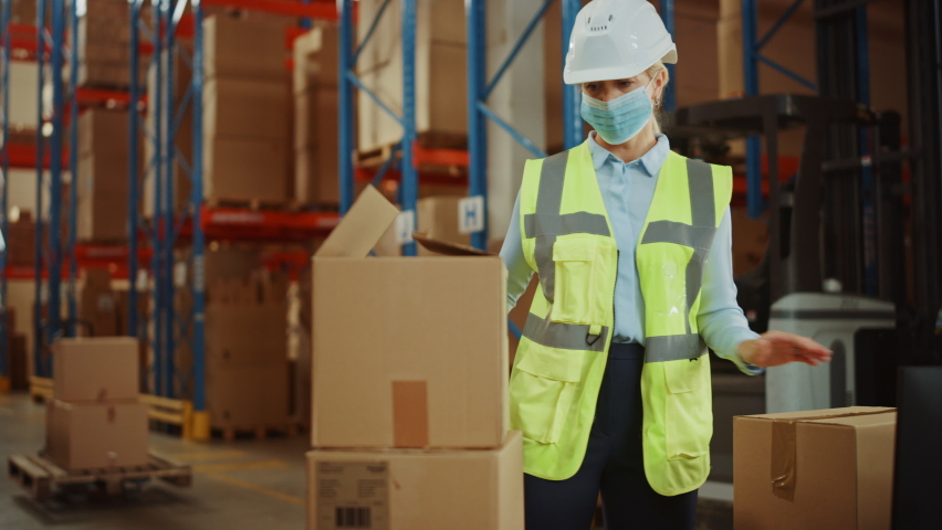 In Retail Warehouse Professional Worker Wearing Facial Mask Packing Parcel, Cardboard Box Sealed with Tape Dispenser Ready for Shipment. Delivery and Distribution Center Full of Shelves with Products | Shutterstock HD Video #1060923442