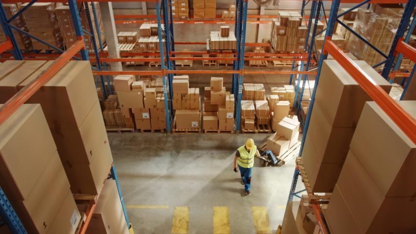 Top-Down Elevating View: Worker Moves Cardboard Boxes using Manual Pallet Truck, Walking between Rows of Shelves with Goods in Retail Warehouse. People Work in Product Distribution Logistics Center | Shutterstock HD Video #1060923475