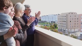 4k video of mother, son and grandparents clapping on the balcony in gratitude to the doctors
