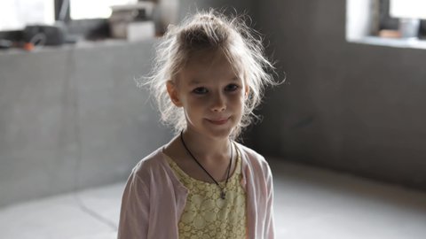 Portrait of poor Orphan emaciated refugee girl standing alone looking at camera. Child loneliness. Sad little child kid. Homeless child is depressed, standing in empty poor house