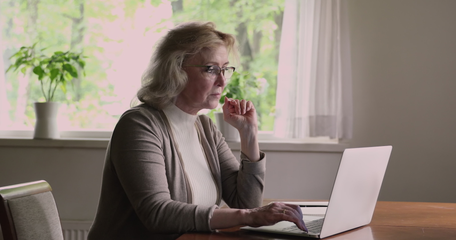 Senior woman sit at table use laptop feels tired of wireless pc usage suffers from blurry vision eyestrain problem, take off glasses relief pain. Dry eyes, aged asthenopia, age related changes concept | Shutterstock HD Video #1060929496