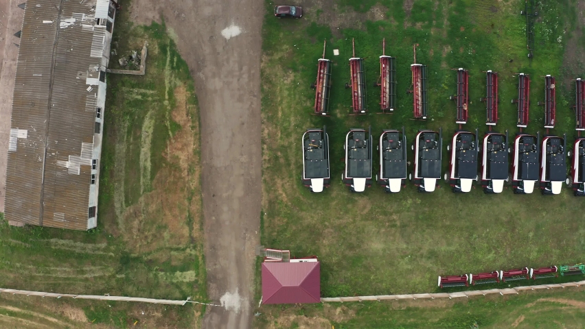 Aerial top down view on a row of new grain harvesters parked on the farm. New farm machines waiting to harvest crops in the fields.

