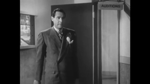 CIRCA 1946 - In this comedy movie, a broadcaster is reunited with his girlfriend and kisses her in the middle of the radio station.