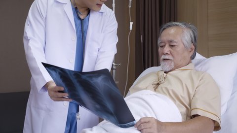 Doctor talking Consultant elderly male patient in hospital. Explain an X-ray about cancer treatment, lung disease and physical health. Retirement or Treatment health insurance. Concept Health care