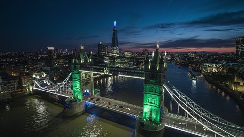 Lit up Tower Bridge, London Skyline, Establishing Aerial View Shot of London UK, United Kingdom at night evening