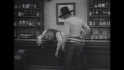CIRCA 1934 - In this western film, a cowboy (John Wayne) enters a saloon filled with dead bodies and the music of a player piano.