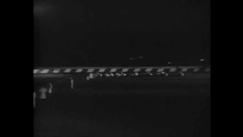 CIRCA 1949 - In this action movie, spectators watch a racecar competition take place at night.