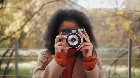 African American woman with analog camera making photo in autumn park, safe travel and explore, hiking tours, black tourist girl in wild forest, generation z lifestyle, teenager photographer portrait